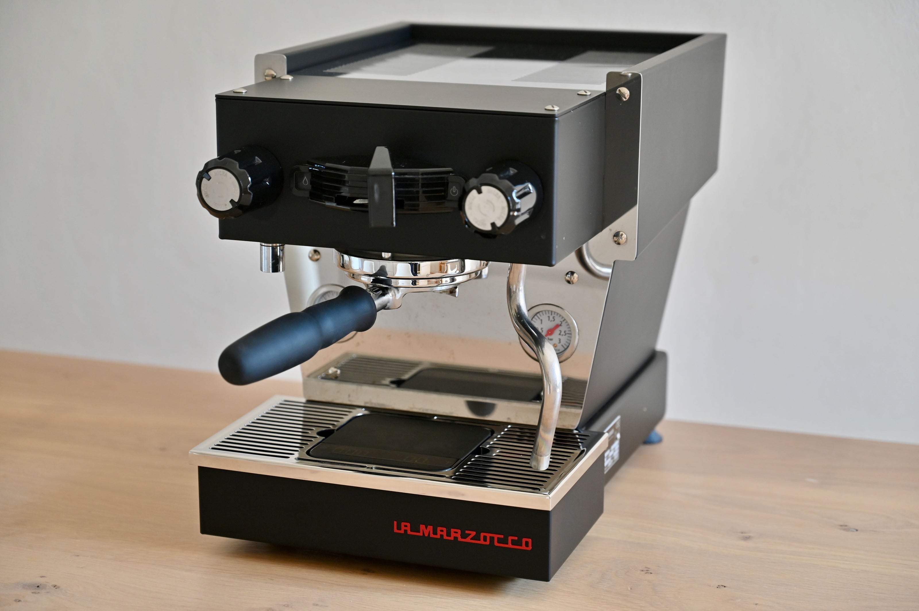 Espresso machine on a wooden surface with a plain background
